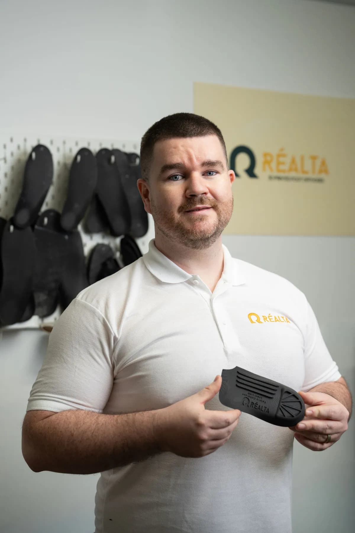 Podiatrist Paul McMullan holding a custom 3D-printed orthotic at Réalta Labs